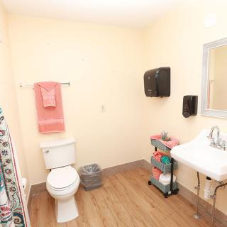 A clean bathroom with a toilet, sink, mirror, and neatly arranged towels.