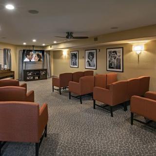 A cozy seating area with comfortable chairs, a television, and framed pictures on the walls.