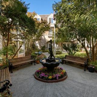 A serene courtyard featuring a central fountain surrounded by lush greenery and benches.