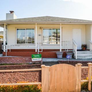 A single-story house with a front porch and small garden, enclosed by a wooden fence.