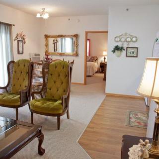A cozy living room featuring vintage green chairs, a wooden coffee table, and traditional decor elements.