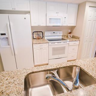 A modern kitchen with white cabinetry, granite countertops, and stainless steel appliances.