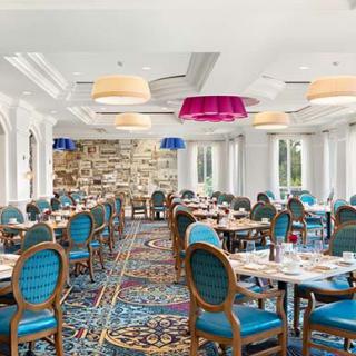 A stylish and elegant restaurant dining room with colorful lighting and well-arranged tables and chairs.