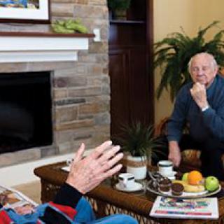 Two seniors having a conversation in a cozy living room setting.