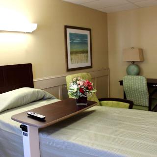 A neatly arranged hospital room with a bed, side table, and comfortable seating.