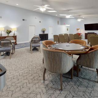 A spacious living and dining area with modern furnishings, including tables and chairs, a television, and a ceiling fan.