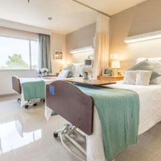 A well-lit, modern hospital room featuring two patient beds.