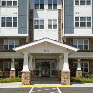 Entrance of a modern apartment building with stone accents and large windows.