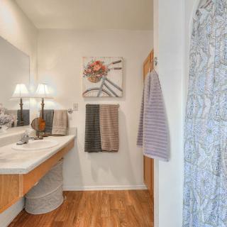 A well-decorated bathroom with a wooden floor, featuring a sink area, mirror, and neatly arranged towels.