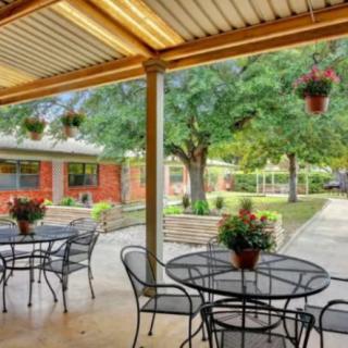A cozy outdoor patio area with metal tables and chairs, surrounded by greenery.