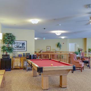 A spacious indoor game room featuring a pool table and comfortable seating areas.