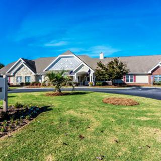 A large residential building with a well-maintained lawn under a clear blue sky.