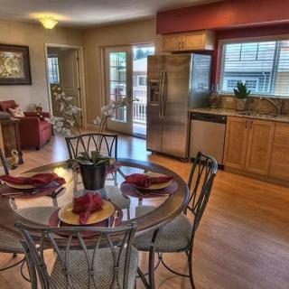 A modern open kitchen and dining area with a glass table set, featuring stainless steel appliances and wood flooring.