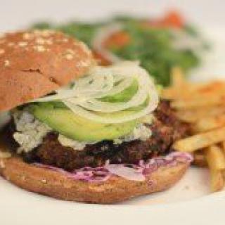 A delicious burger with avocado and onion, served with a side of fries.
