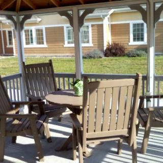 A cozy gazebo featuring a wooden table and chairs on a sunny day.