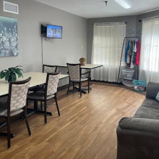 A cozy living and dining space featuring comfortable seating, a television, and natural light.