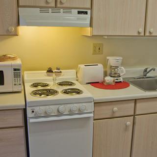 A small kitchen setup with essential appliances including a stove, microwave, toaster, and coffee maker.