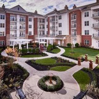 A beautifully landscaped courtyard in front of a multi-story residential building.