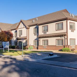 A modern two-story residential building with a well-maintained exterior and ample landscaping.
