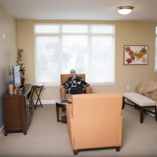 A cozy living room with a person sitting in an armchair, watching television.