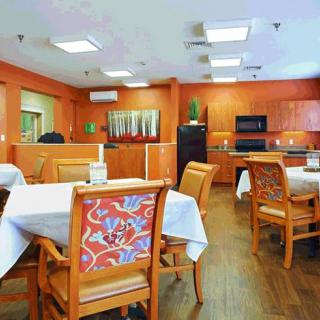 A cozy dining room with neatly arranged tables and vibrant orange walls.