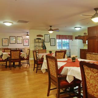 A cozy dining room with neatly arranged tables and chairs, featuring warm lighting and tasteful decor.