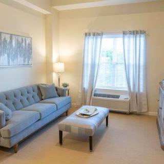 A cozy living room with a blue sofa, coffee table, and large window with curtains.