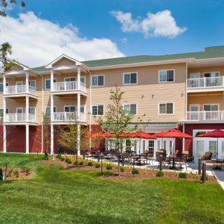 A modern hotel building with multiple balconies and a landscaped outdoor seating area.