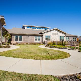 A modern residential building with a well-maintained lawn and clear blue sky.