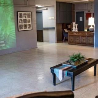 A cozy lobby area featuring a reception desk, decorative plants, and artwork on the wall.