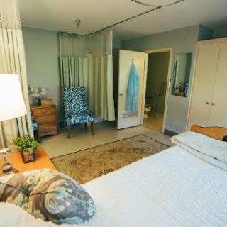 A cozy and well-decorated bedroom featuring a comfortable bed, stylish chair, and tasteful decor.