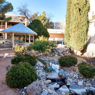 A serene garden featuring a flowing stream, decorative rocks, and a charming gazebo.