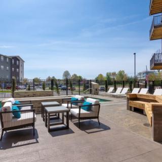 A modern outdoor patio with comfortable seating near a pool at an apartment complex.