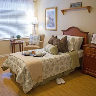 A cozy and well-decorated bedroom with a bed, nightstand, chair, and window.