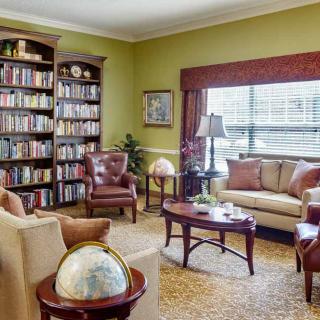 A cozy living room with a large bookshelf, leather chairs, and a sofa surrounding a coffee table, accented by a globe.