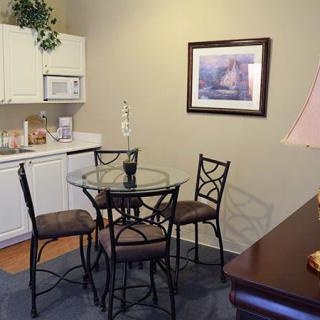 Cozy kitchen and dining area with a glass table and chairs, featuring cabinets, a microwave, and wall art.