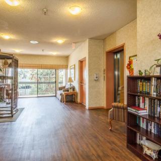 A cozy hallway with a wooden floor, bookshelves, and a seating area by the window.