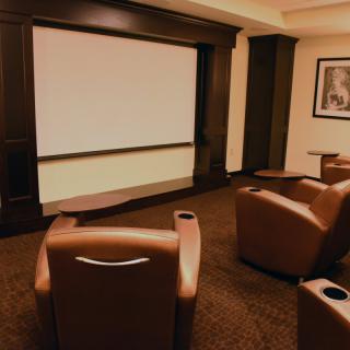 A cozy home theater with comfortable seating facing a large screen.