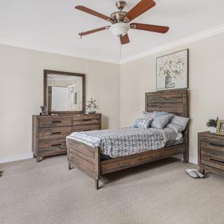 A cozy bedroom featuring a wooden single bed, matching dresser and nightstand, with a ceiling fan overhead.