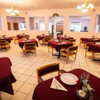 A spacious restaurant dining area with neatly arranged tables and chairs, adorned with elegant chandeliers.