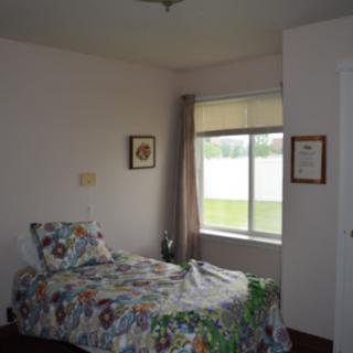 A cozy bedroom featuring a single bed with colorful bedding and natural light streaming through the window.