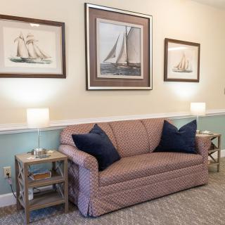 A cozy living room with a sofa, nautical-themed paintings, and ambient lighting.