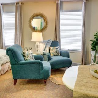 A cozy living room with blue armchairs, a coffee table, and warm lighting.