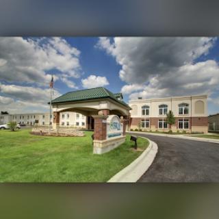 A well-designed entrance of a modern building set against a partly cloudy sky.