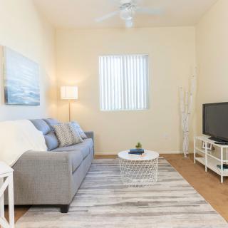 A cozy and minimalist living room featuring a gray sofa, a TV, and subtle lighting.