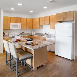 A modern kitchen with wooden cabinets, an island, and various appliances.