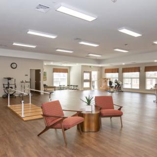 A spacious and well-lit gym with exercise equipment and seating area.