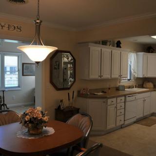 A cozy kitchen with a dining area, featuring white cabinets and a central light fixture.