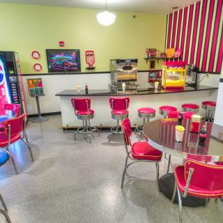 A retro-style diner with vintage decor, featuring red seating and a popcorn machine.