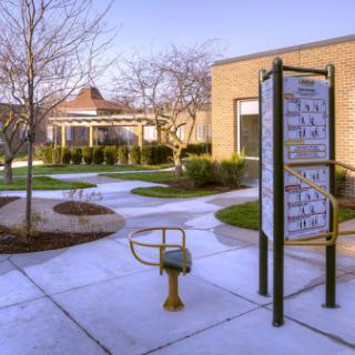 A serene park area with a pathway, a bench, and informational signage surrounded by trees.